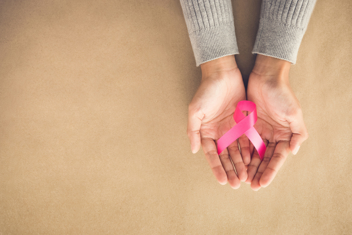 Woman hands giving satin pink ribbon, supporting symbol of breast cancer awareness campaign in October,